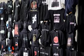 Black hoodie collection featuring graphic prints, streetwear designs, and logo patterns displayed on a wall at Hypebot store. Perfect for fans of urban fashion and music-inspired apparel.