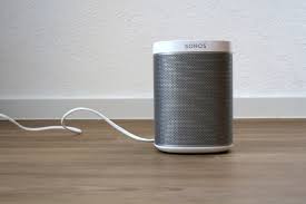 Sonos portable speaker on wooden surface with power cable in background, highlighting portable music streaming device for modern audio experiences.