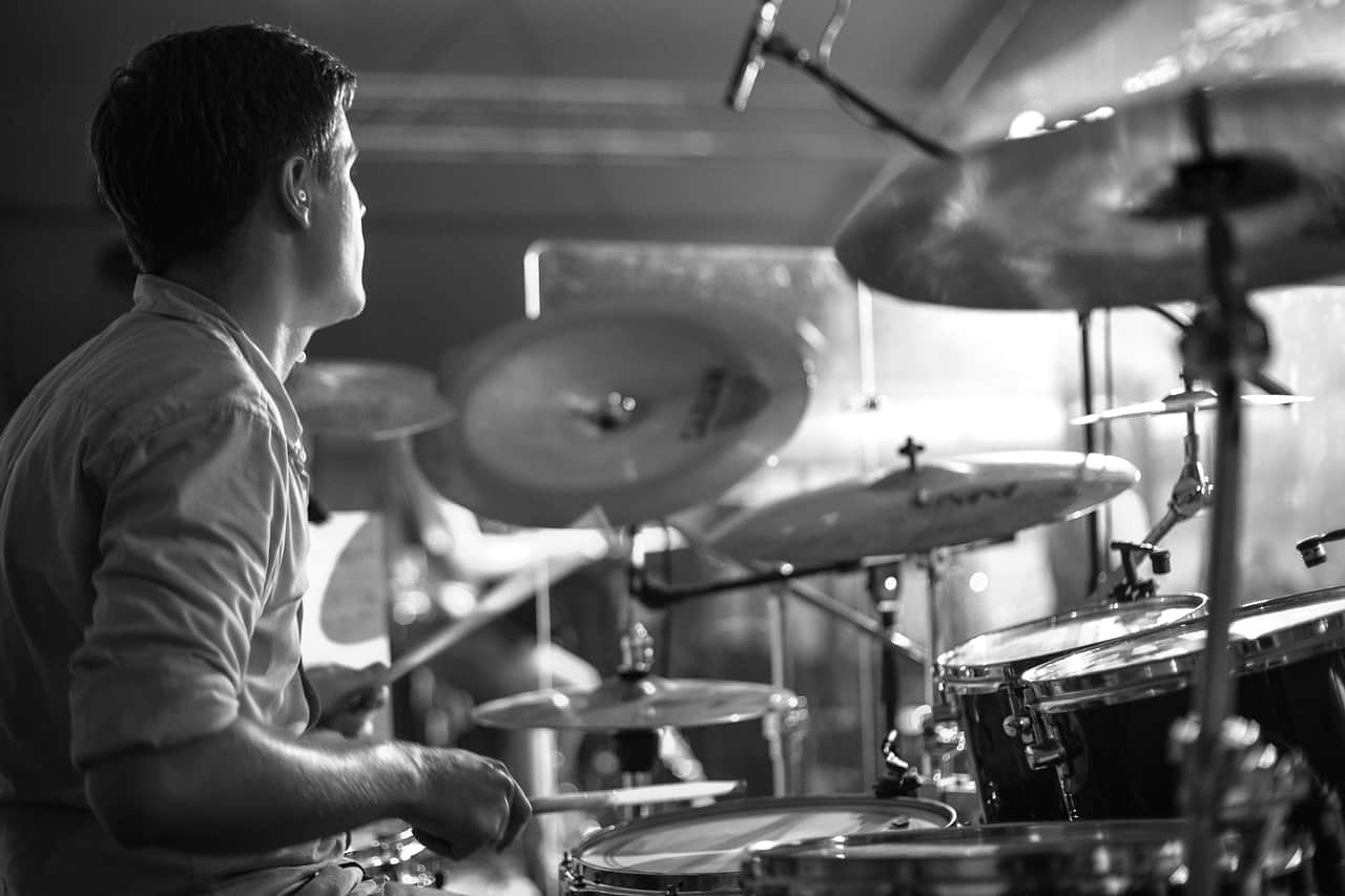 A man playing the drums in a music studio, focusing on the rhythm and percussion, black and white photo.