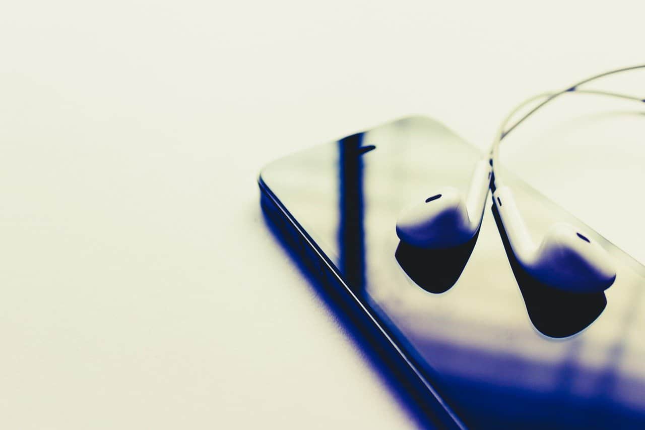 Wireless earbuds resting on a smartphone with a reflective screen, modern audio technology for music streaming and hands-free calls.