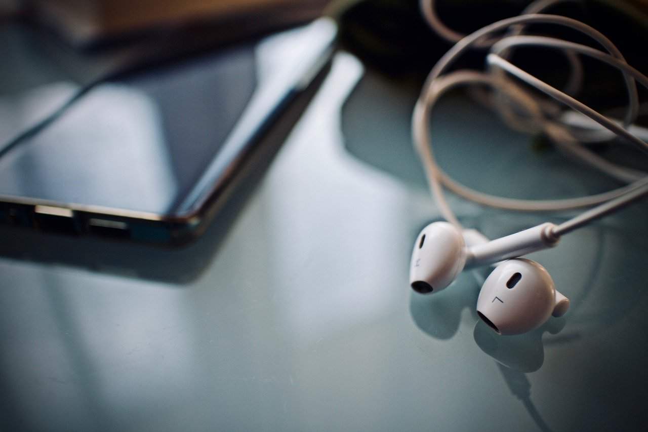 Wireless earbuds and smartphone on a modern desk, highlighting tech gadgets and mobile accessories.