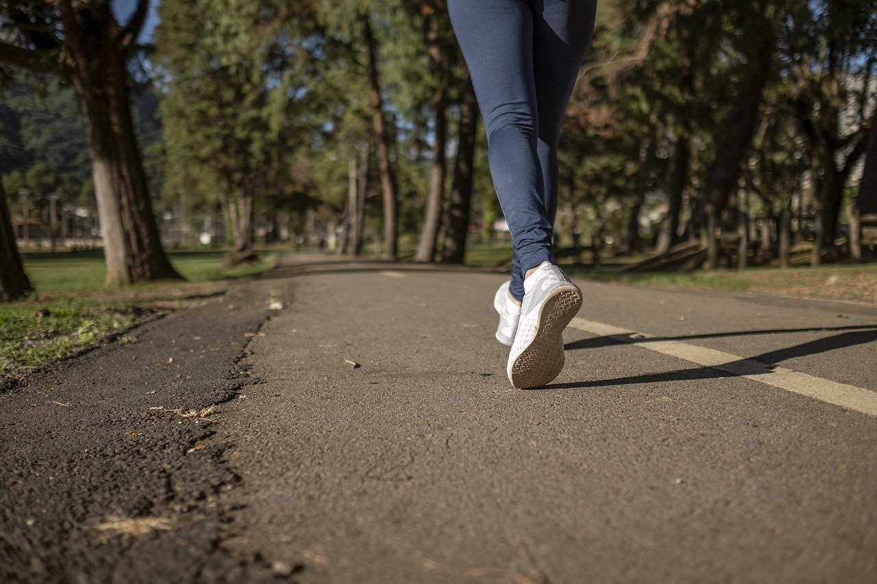 Running outdoors on a paved trail surrounded by trees, athletic shoes, fitness, wellness, exercise, outdoor recreation, healthy lifestyle, marathon training, jogging, nature walk, fitness motivation, active lifestyle, exercise routine, outdoor fitness.