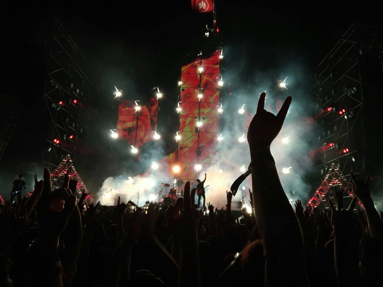 Vibrant music concert at night with energetic crowd and colorful stage lighting, capturing the lively atmosphere of a live performance and audience engagement.