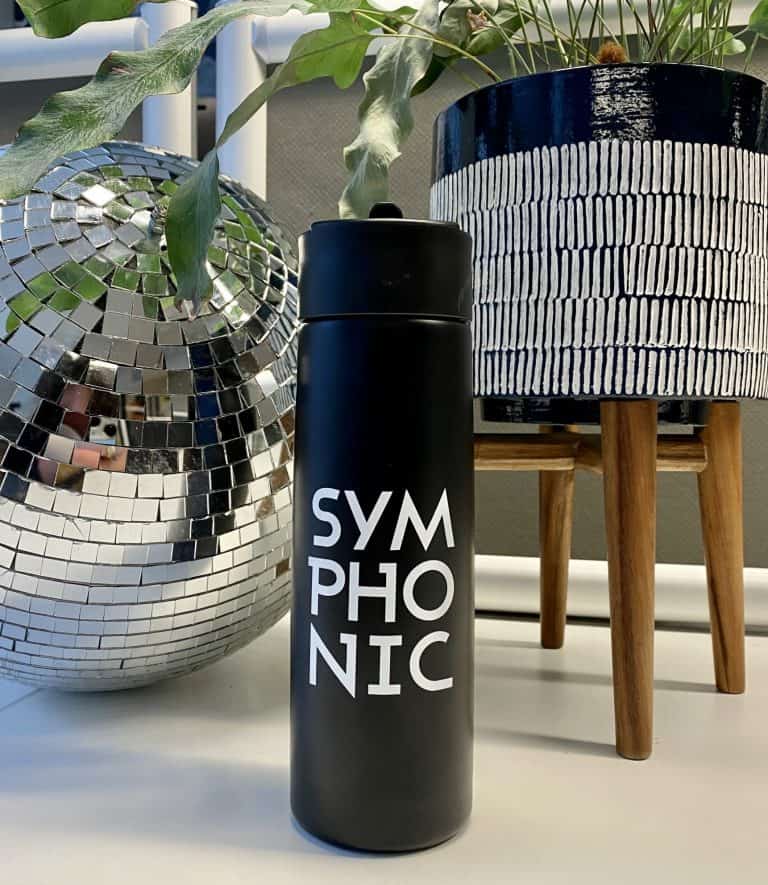 Symmetric black water bottle with white text modern office decor with reflective disco ball and potted plant stylish workspace accessories.