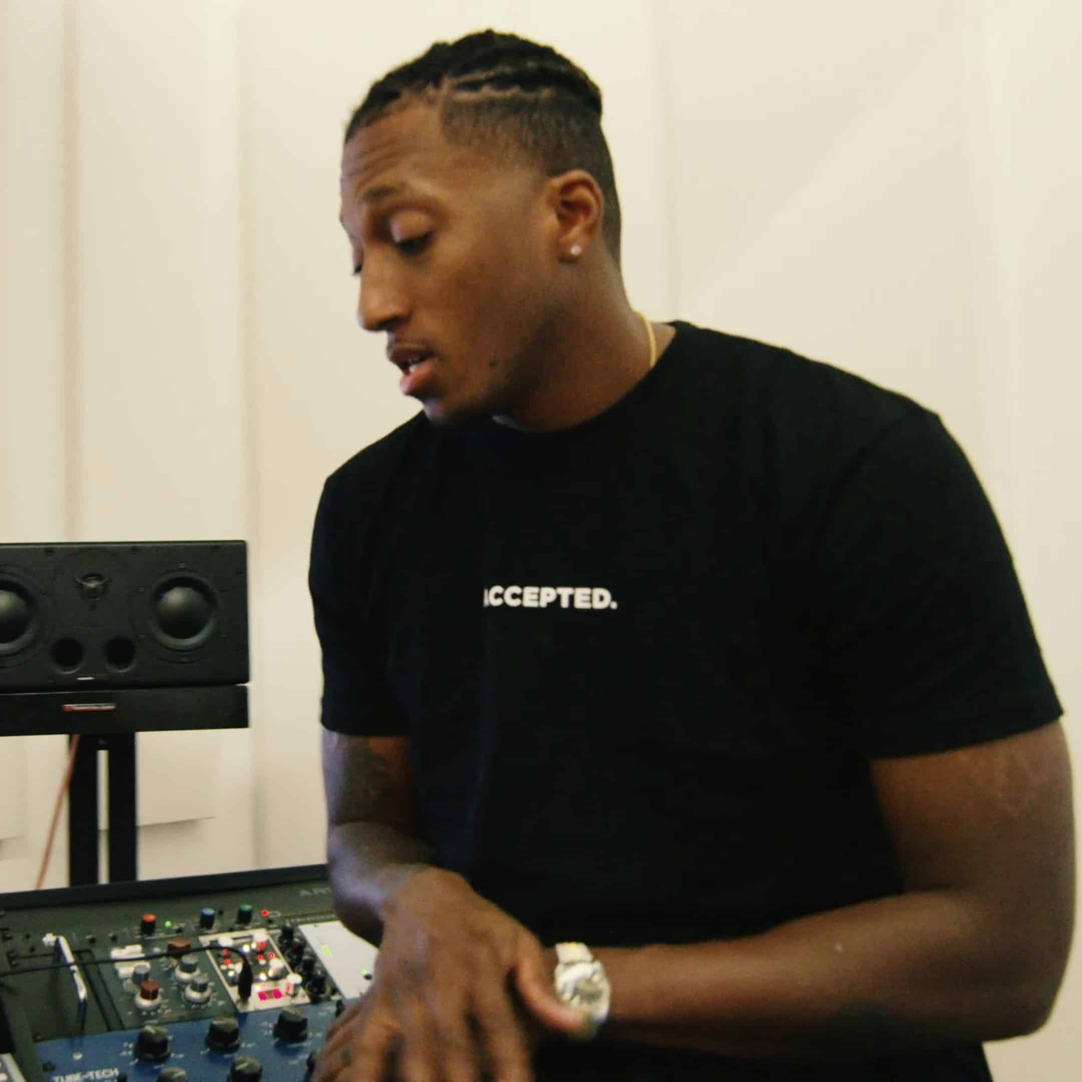 Young male music producer working with professional audio equipment in a modern studio setting.