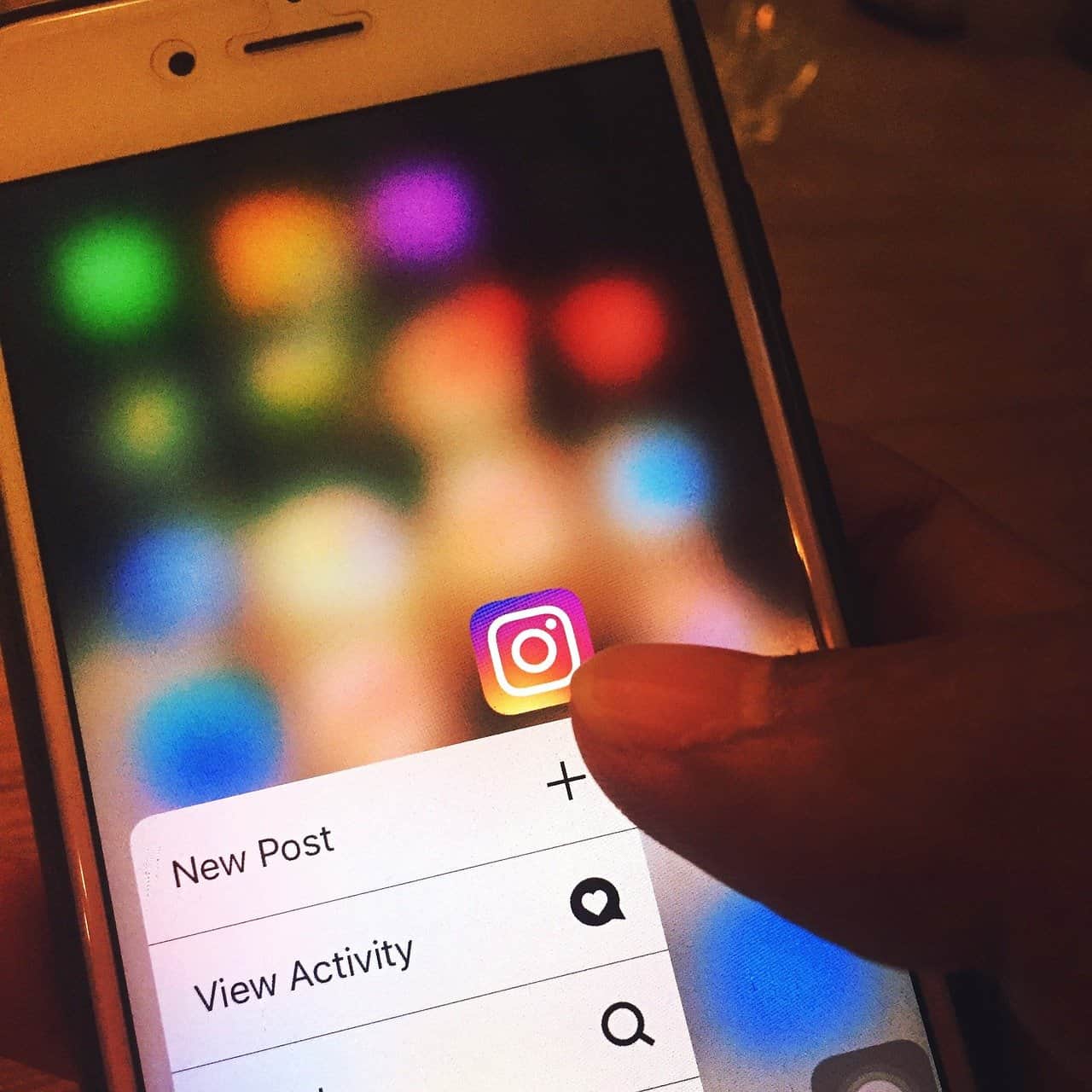 Instagram logo on smartphone screen, social media app icon, mobile device, digital marketing, photo sharing, social networking, influencer marketing, mobile app interface, social media management, online engagement.