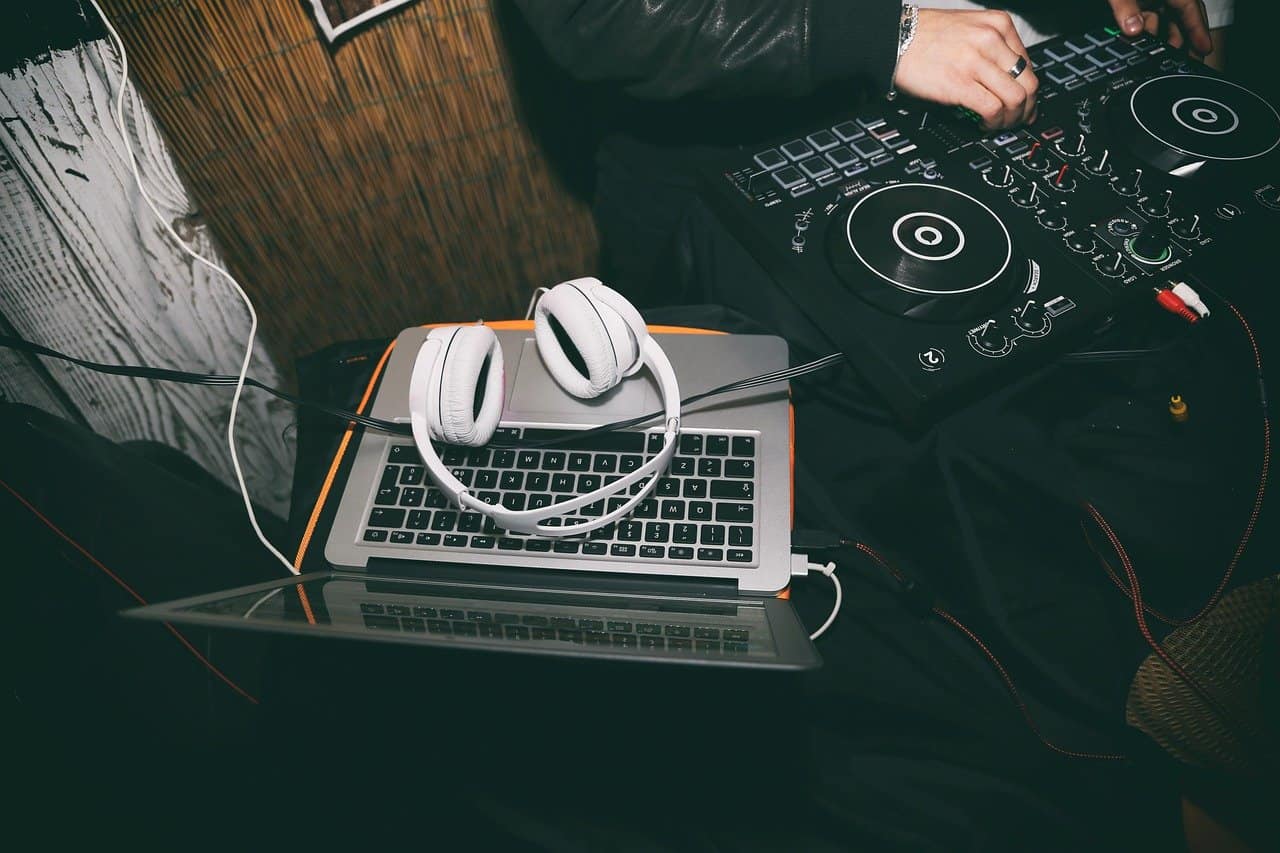 DJ controller and headphones setup for music production or DJing, showcasing electronic music equipment on a laptop and mixer for live performances or studio sessions.
