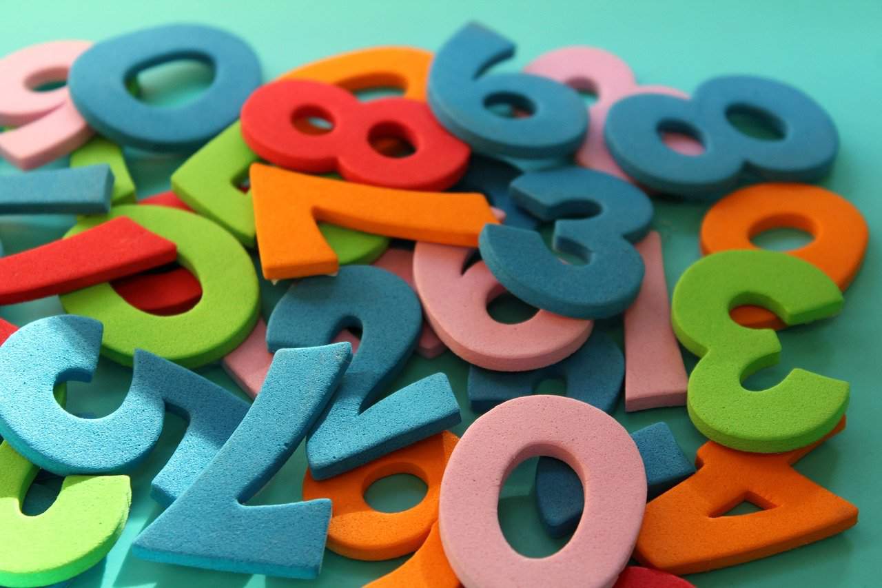 Colorful foam numbers scattered on a pastel background for educational and learning activities.