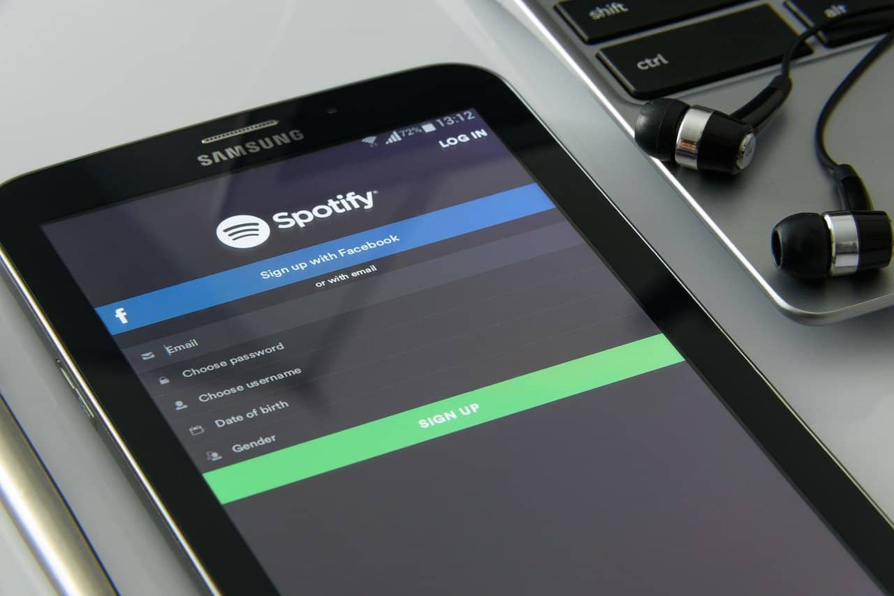 Spotify login screen on a Samsung smartphone with earphones nearby, representing music streaming and digital entertainment platforms.