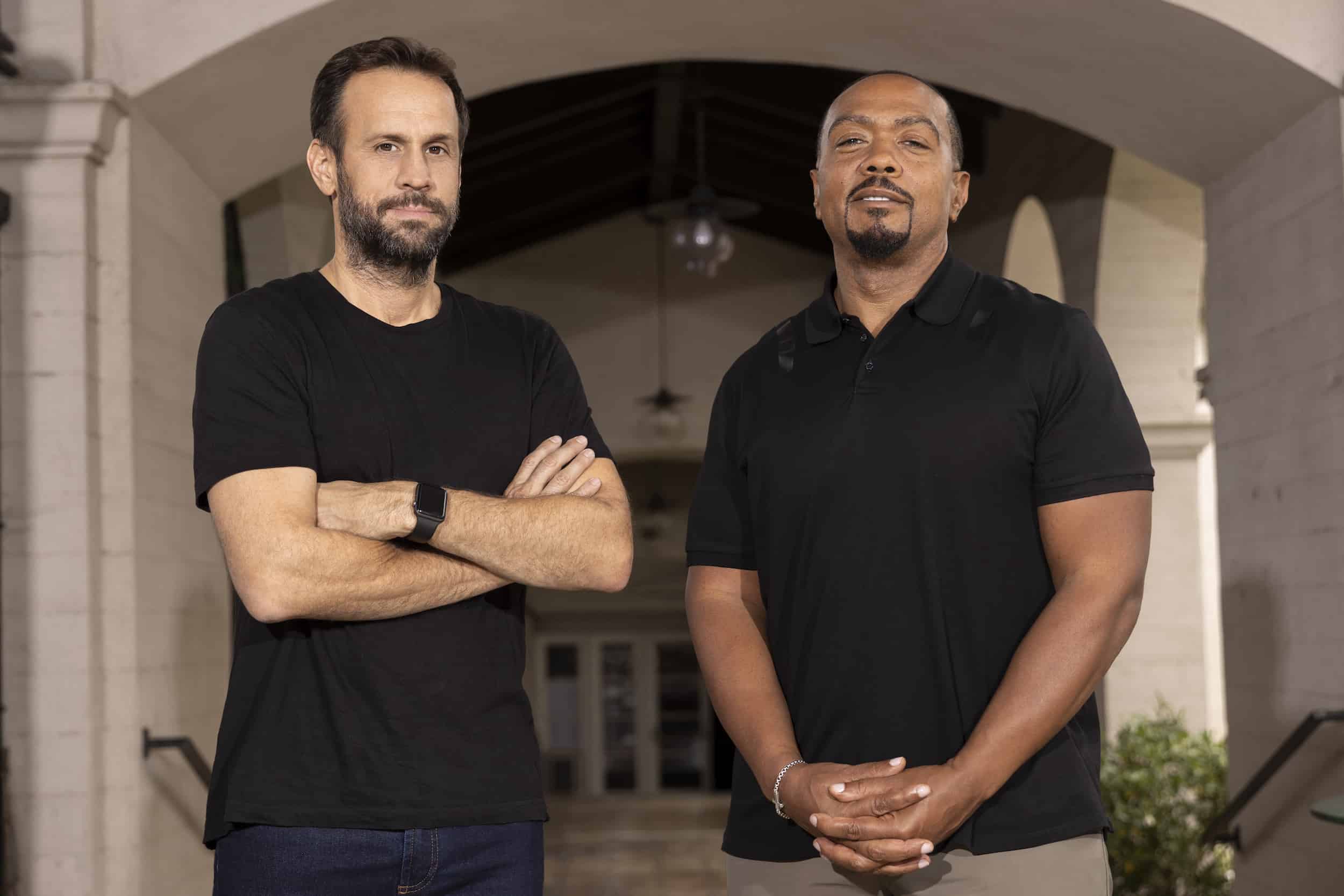 Professional male entrepreneurs standing outside in casual black attire for business networking or podcast interview.