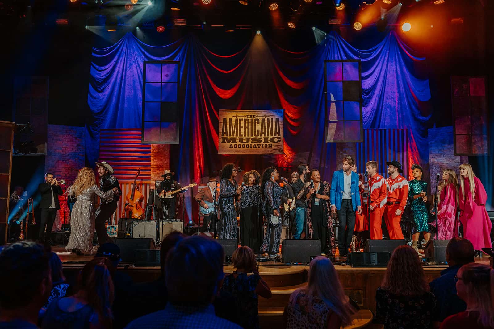 Live music performance at the Americana Music Association event with diverse artists on stage, vibrant lighting, and an enthusiastic audience.