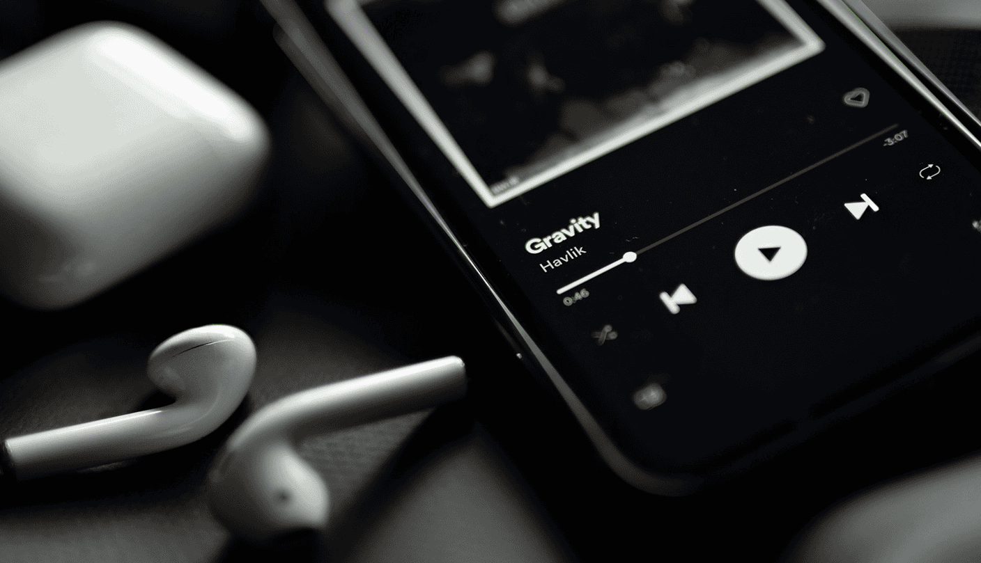 Music streaming on smartphone with earphones, showing the song "Gravity" by Havlik, in a sleek black interface.