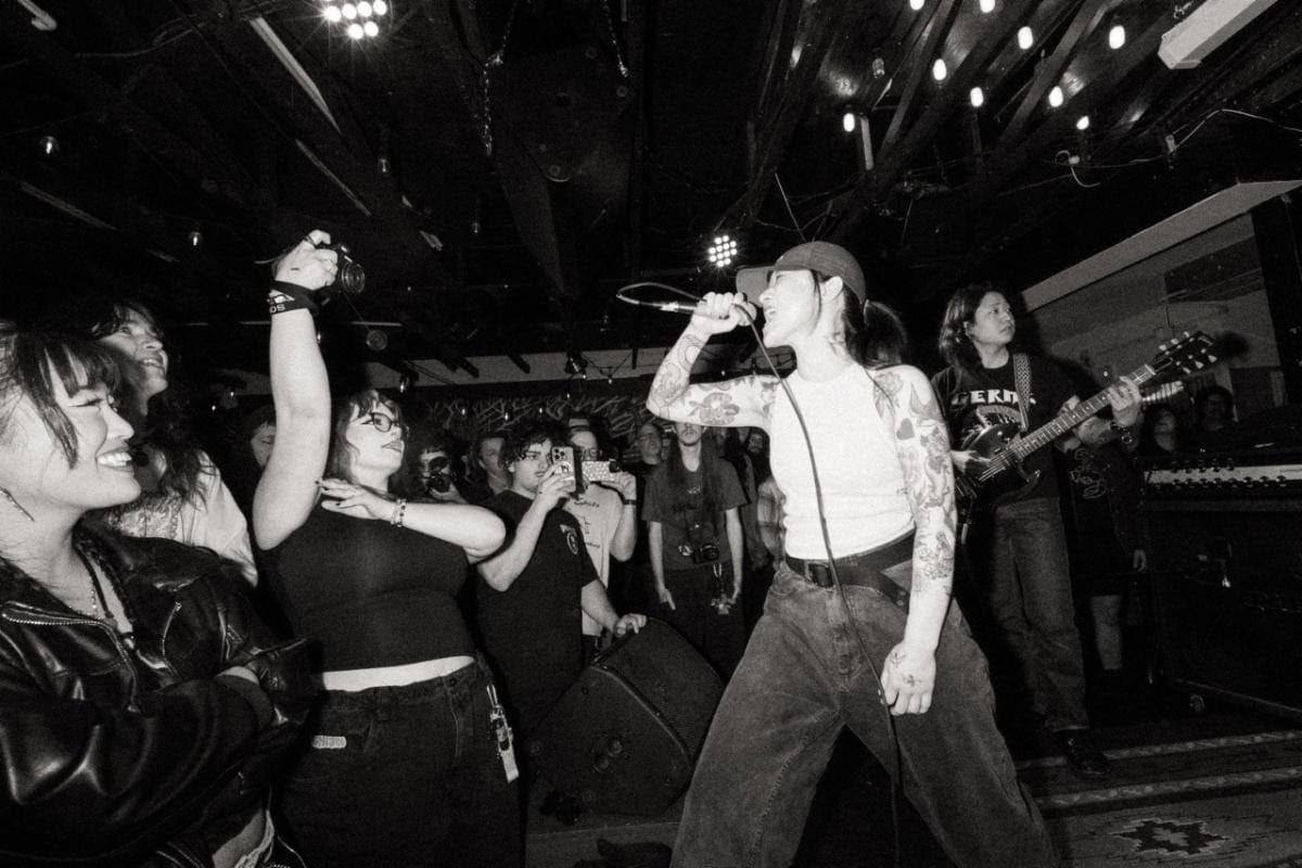 Vocalist performing at a live music venue with an audience enjoying the concert.