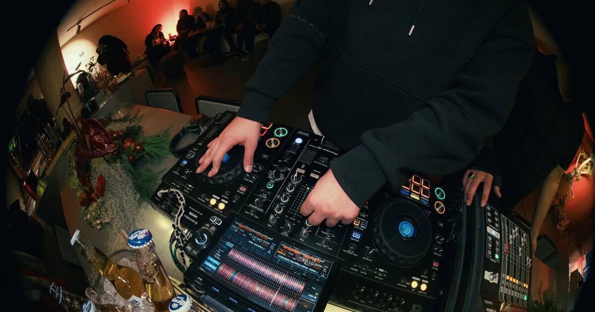 1. DJ mixing music at a live event with professional gear, illuminated by colorful lights, in a vibrant nightclub or concert setting.