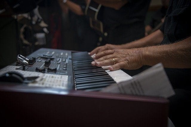 Professional musician playing keyboard during live performance, showcasing music production and artist techniques at a concert or studio.