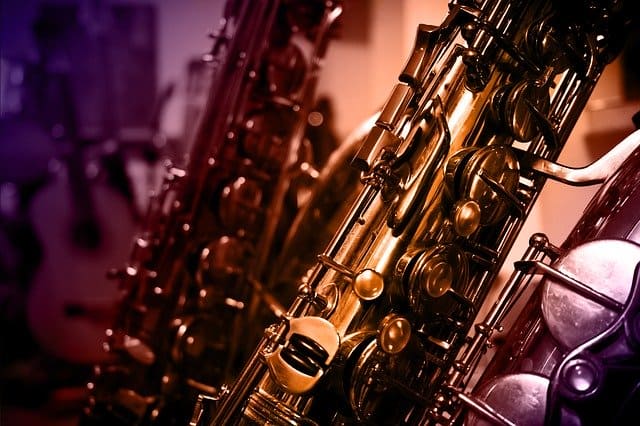 Shiny gold and silver saxophones hanging in a music store, showcasing musical instruments and jazz or blues music themes.