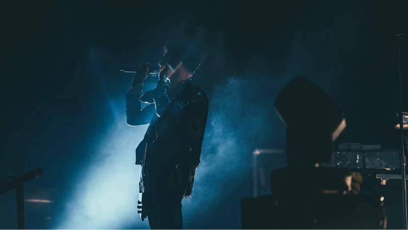 Music artist performing live on stage with dramatic lighting, capturing the essence of the music industry and concert experience.