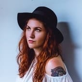 Young woman with red hair wearing a black hat, stylish influencer portrait.