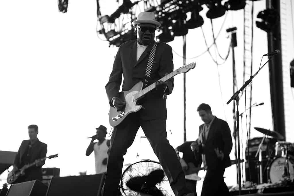 Guitarist performing live on stage at music concert, showcasing electric guitar skills in front of an audience.