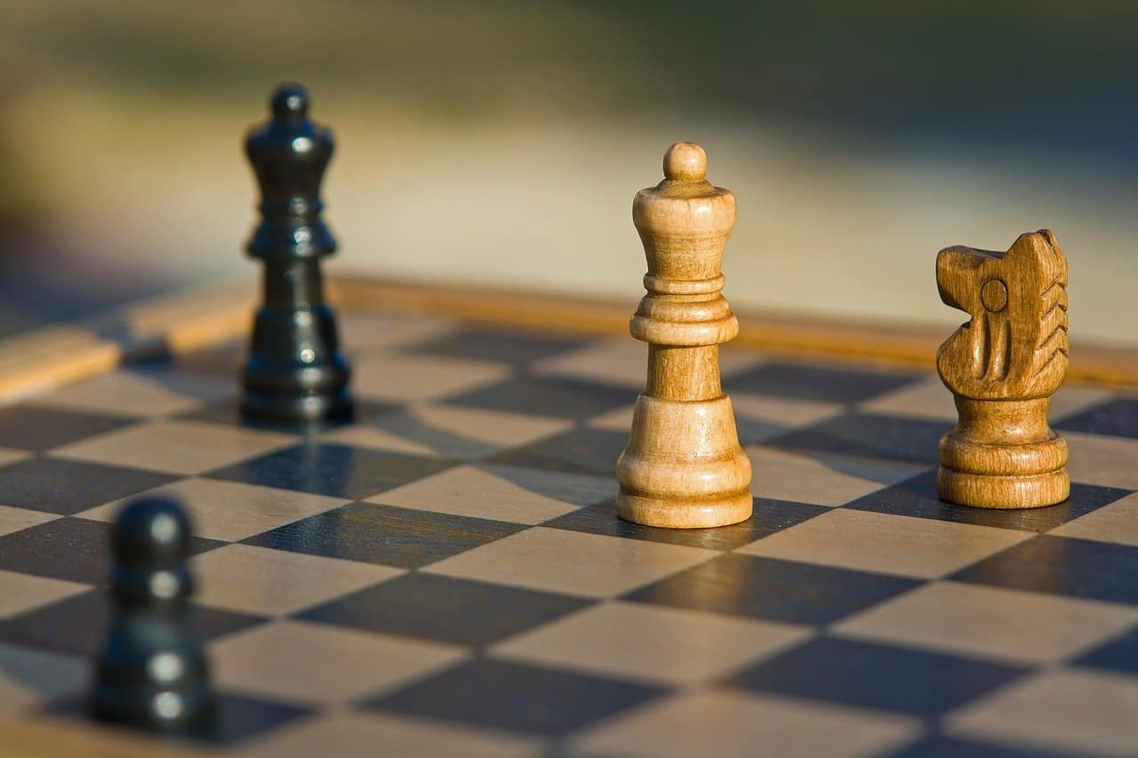 Chess game with wooden and metal pieces on a checkered board, symbolizing strategy and competition, relevant for content related to gaming, board games, and strategic thinking.