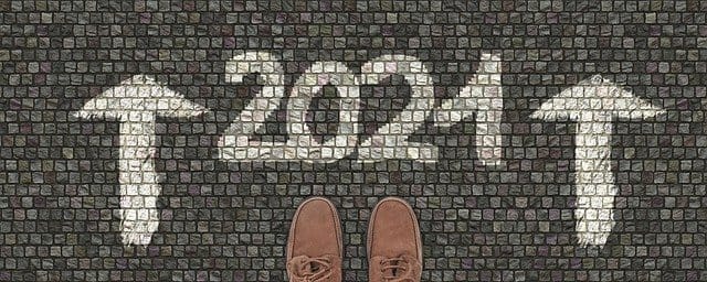 Innovative chalk art of "2024" with upward arrows on cobblestone sidewalk symbolizing new beginnings and forward-looking trends.