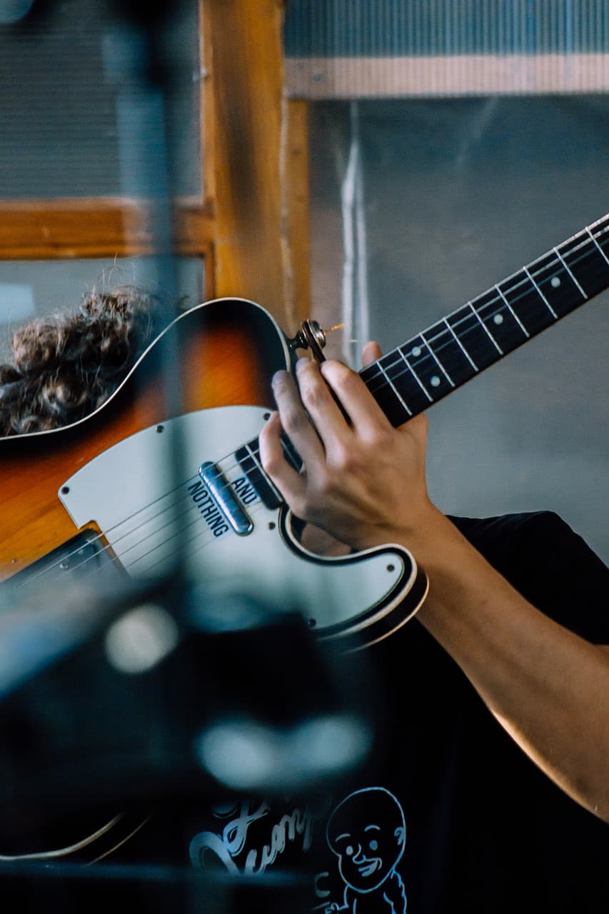 Playing electric guitar in a music studio, focusing on guitar skills and musicianship.