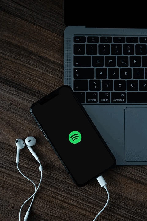 Music streaming on mobile device with headphones and laptop, digital music, technology, and entertainment concept.