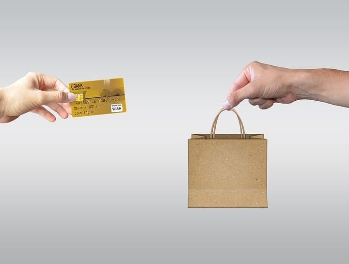 Credit card transaction with small paper shopping bag, e-commerce, online shopping, digital payment, retail, consumer purchasing, cashless payment, financial transaction, shopping online, payment method, digital commerce, checkout process, contactless payment.
