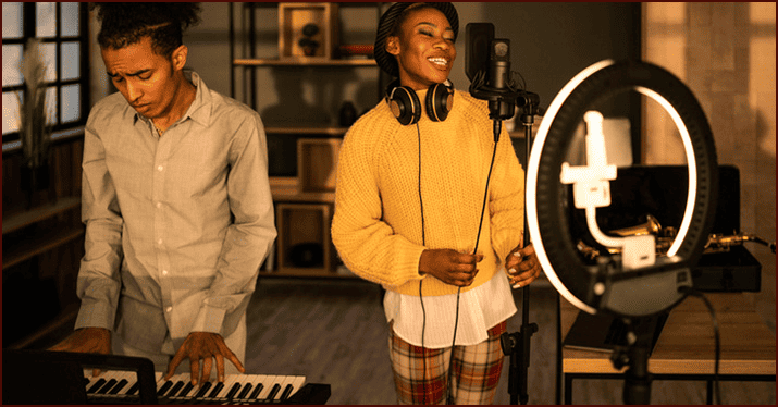 Young music artists recording a song in a professional studio with audio equipment and keyboard.