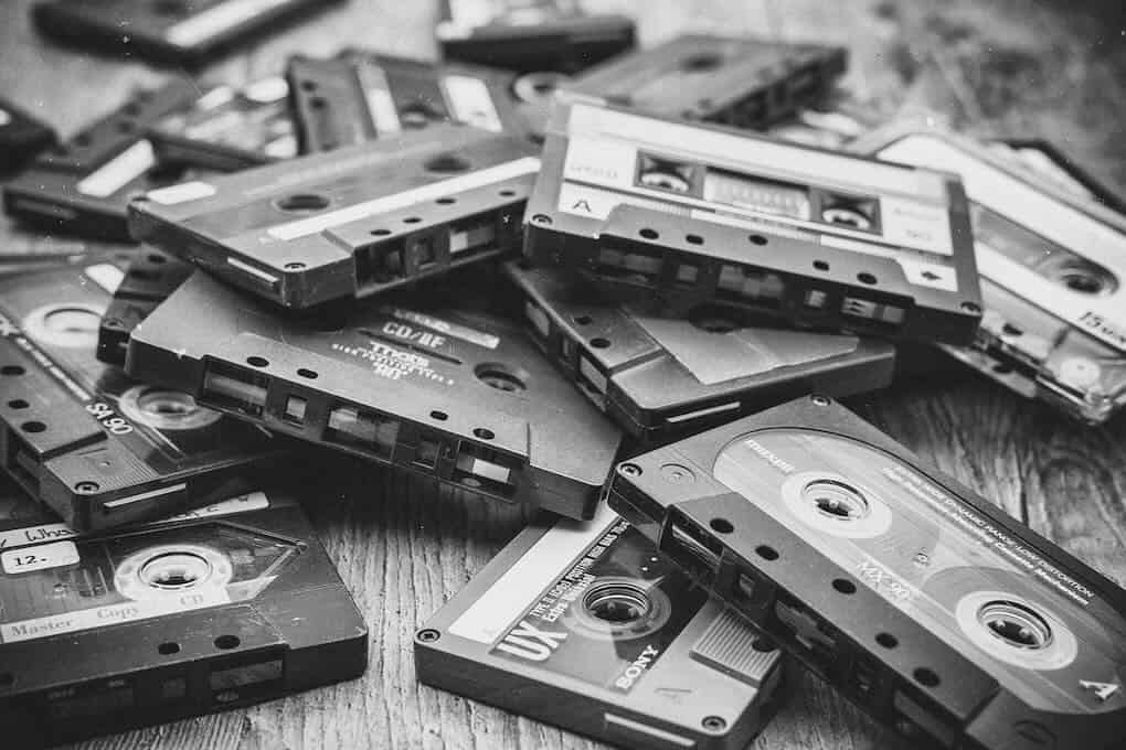 Vintage audio cassette tapes scattered on a wooden surface, representing music recording, mixtapes, and retro audio technology. Ideal for articles on music history, nostalgia, and audio branding.