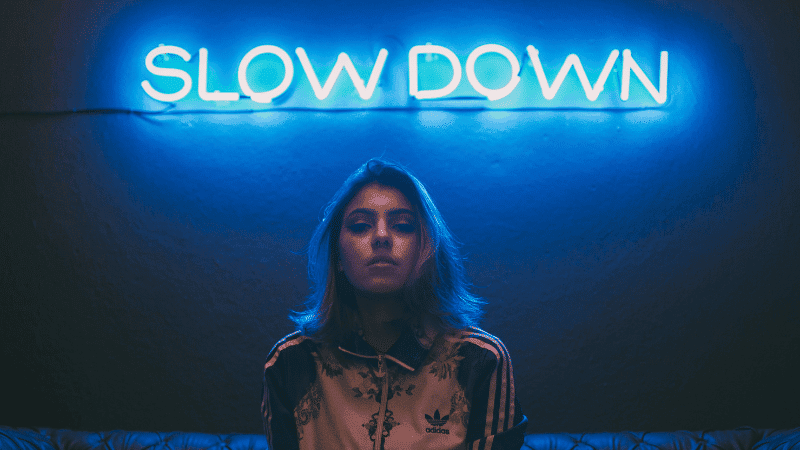 Slow down neon sign with young woman in moody setting for music or lifestyle branding.