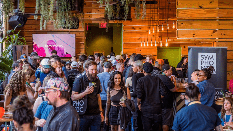 Crowd of music industry professionals attending Hypebot event at Synphony, networking and enjoying live music in a stylish wooden venue with vibrant atmosphere.