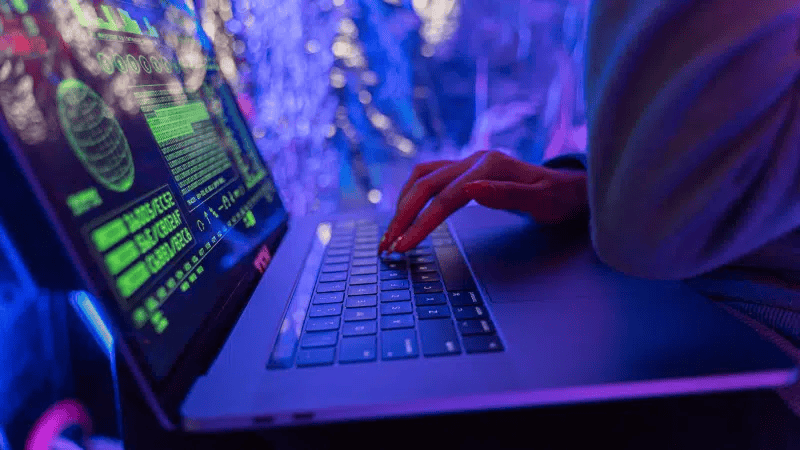 Futuristic hacker working on a laptop with cyber security alerts and digital interface, emphasizing cybersecurity and hacking themes.