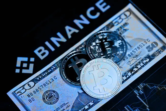 Binance logo with Bitcoin coins on a $50 bill