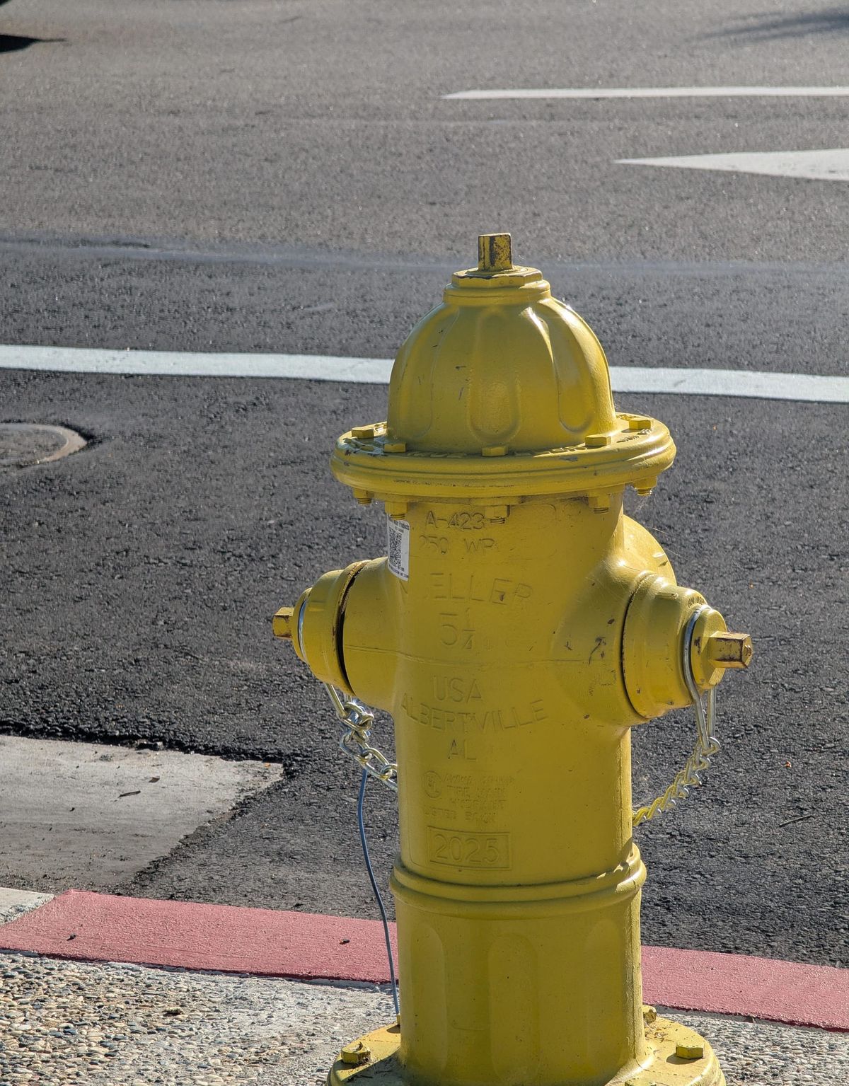 A yellow fire hydrant facing a busy street