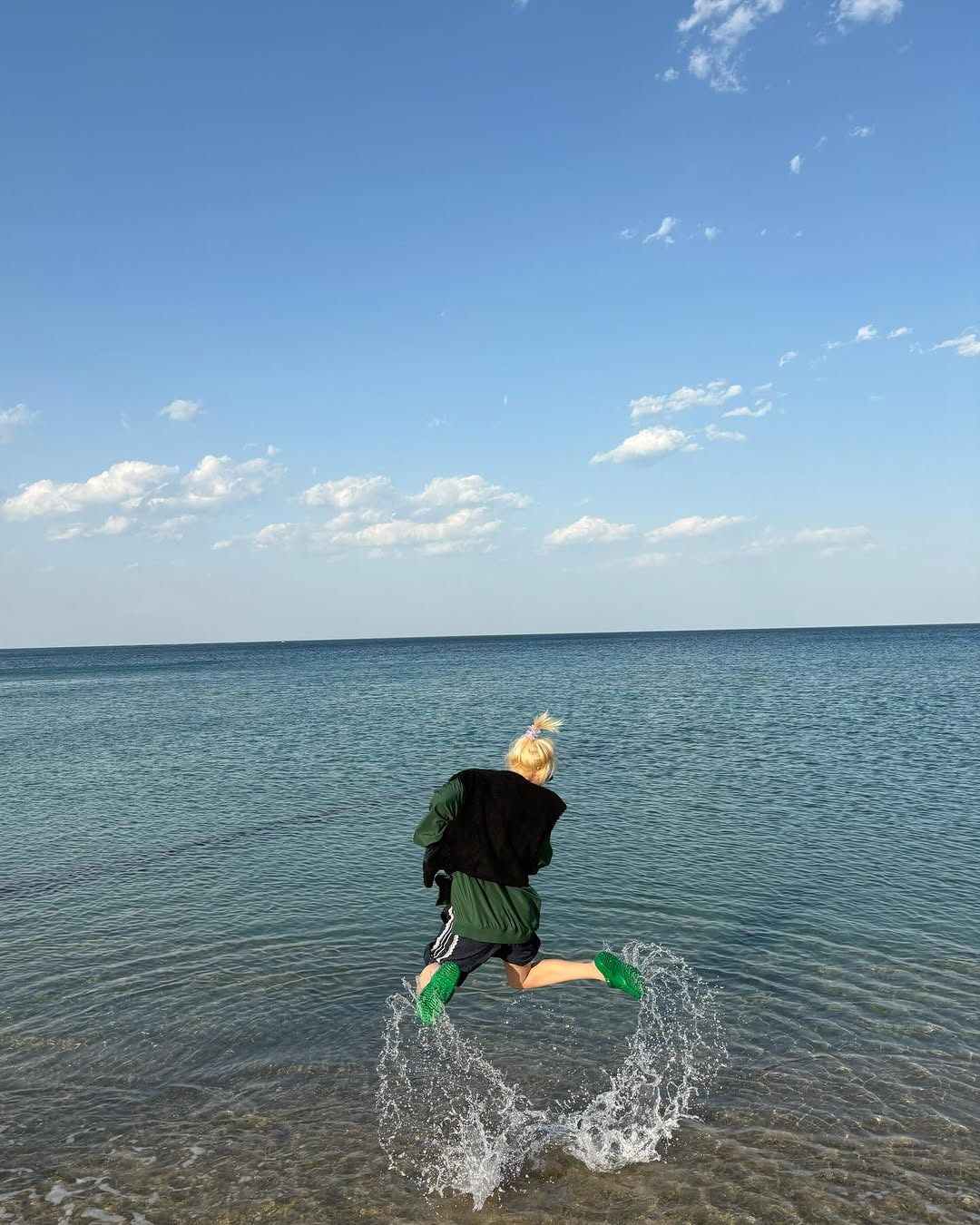 Siyeon taking an image of her jumping up from the water at the beach.