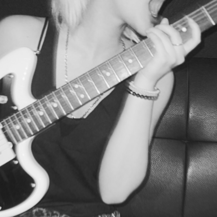 Black and white photo of Siyeon holding a guitar, seeming to yell out while doing so.