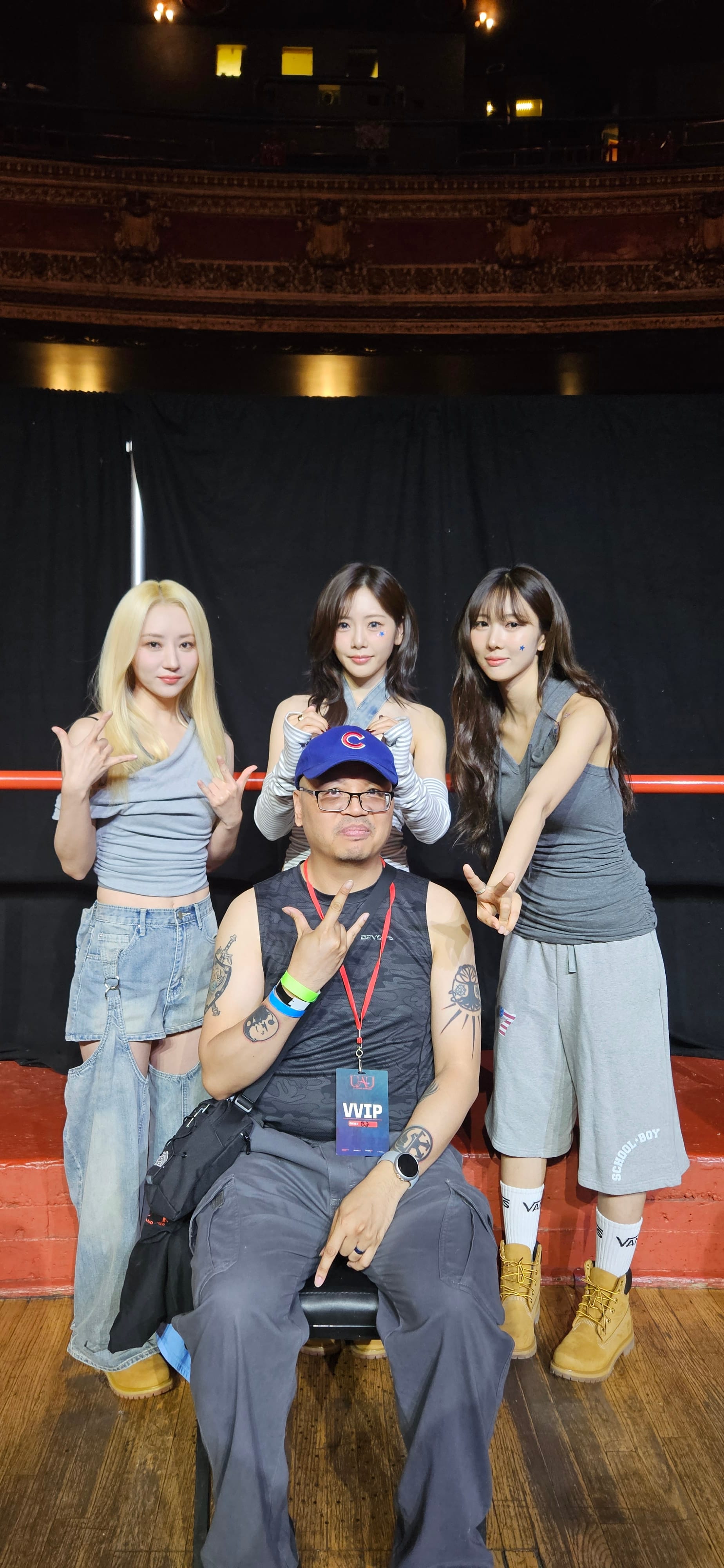 UAU group photo standing behind fan, posing with V and rock signs.