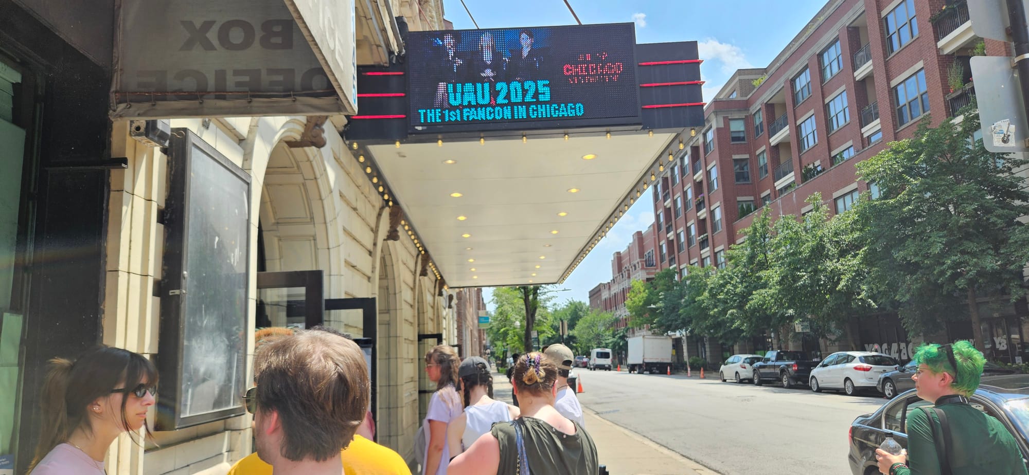 People standing in line outside the Vic Theatre with UAU LED banner displaying.