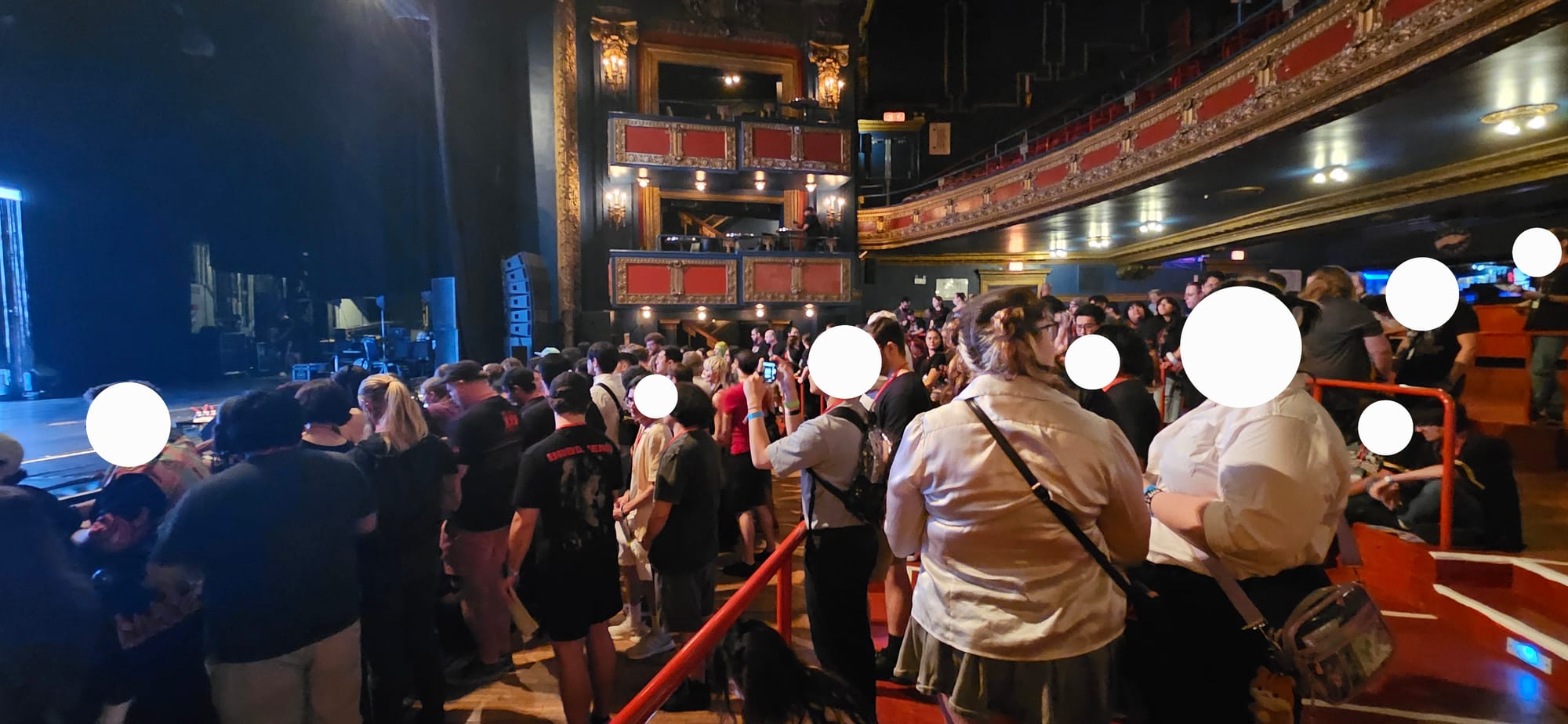 Theatre setting with crowd of people standing and waiting.