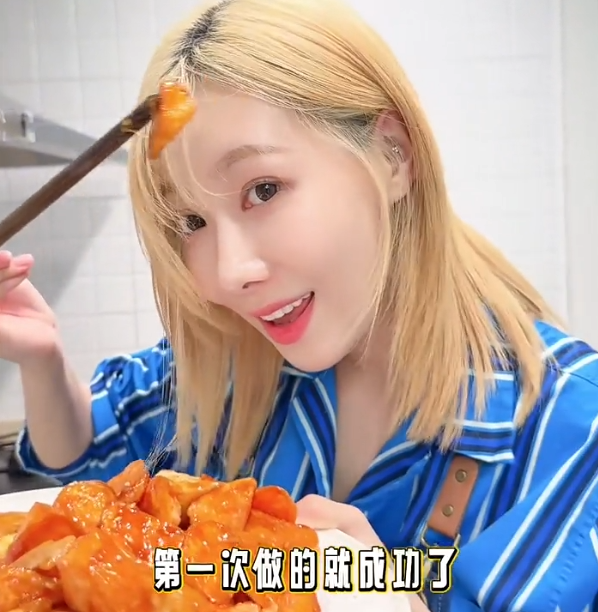 Handong smiling as she displays food she's cooked for the camera.