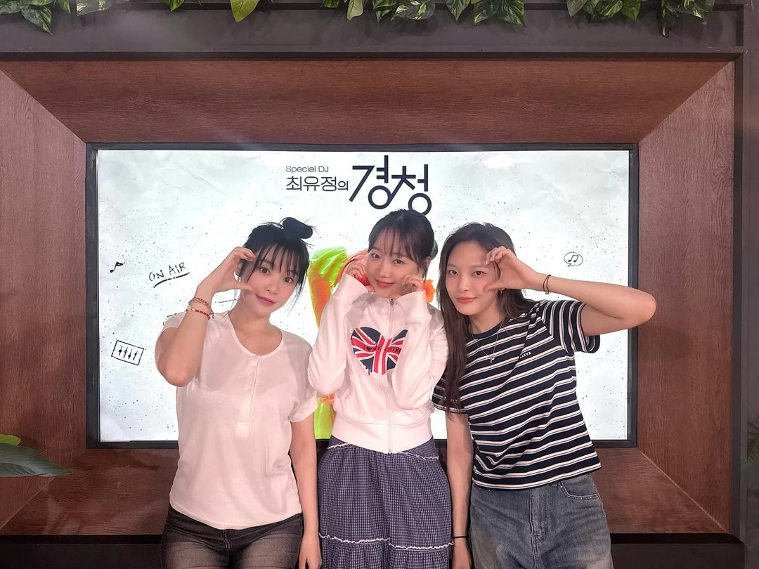 Gahyun, Yoojung and Moon Sua posing for the camera making heart hands.
