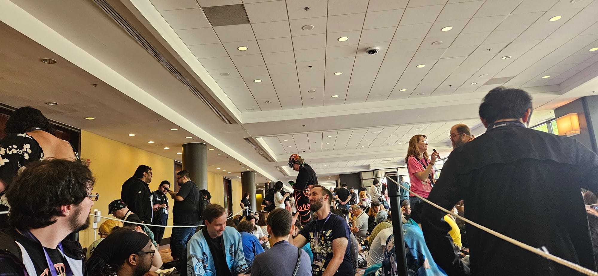 Picture of a zig-zagging line separated by ropes and stanchions with people waiting for the concert.