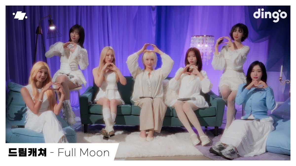 Dreamcatcher, dressed mostly in white, forms hearts to the camera for the dingo live video picture.