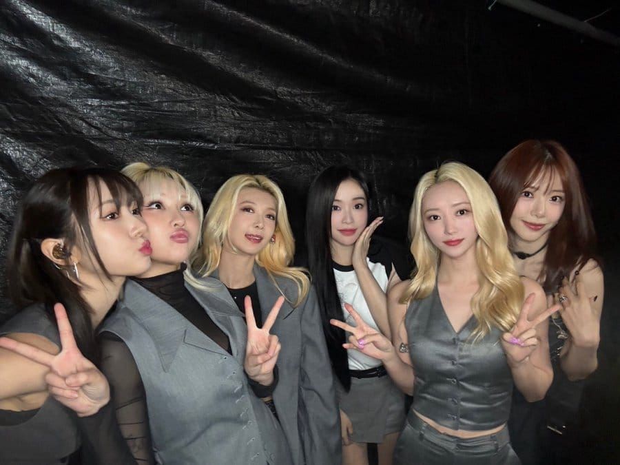 Dreamcatcher, without Handong, smiles for the camera against a black background wearing grey.