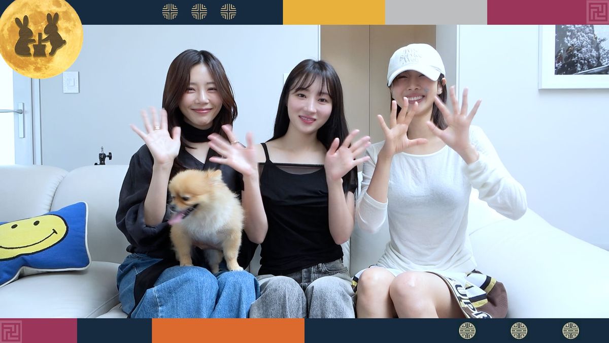 JiU, SuA, and Yoohyeon sitting in an office waving to the camera with Yoohyeon's dog Pie.