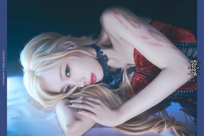 Handong lying down with a black and red outfit and unidentified marks on her arms.
