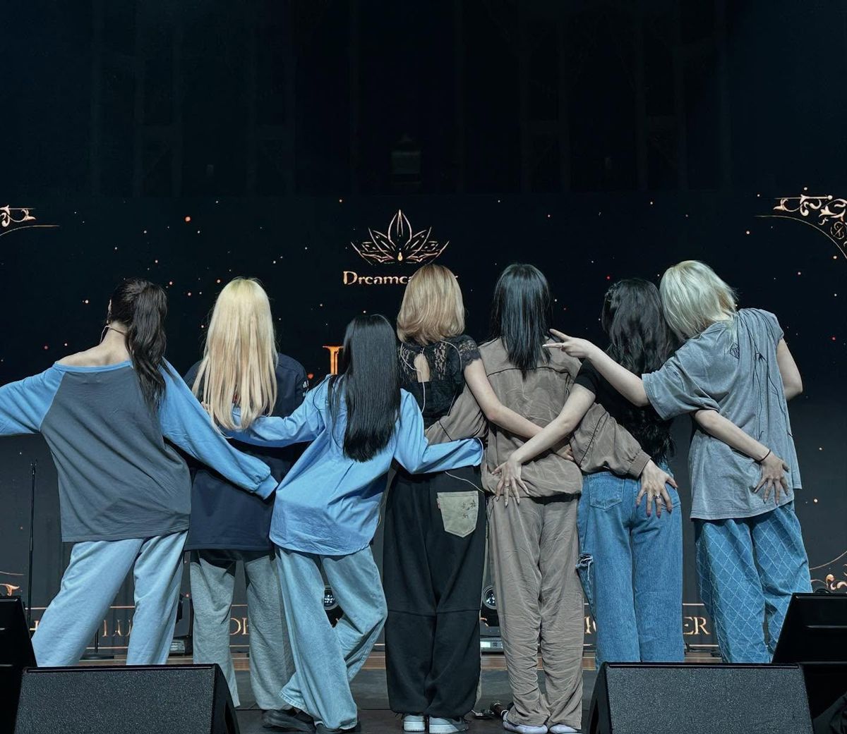 Dreamcatcher with their backs to the camera looking at their stage logo LED.