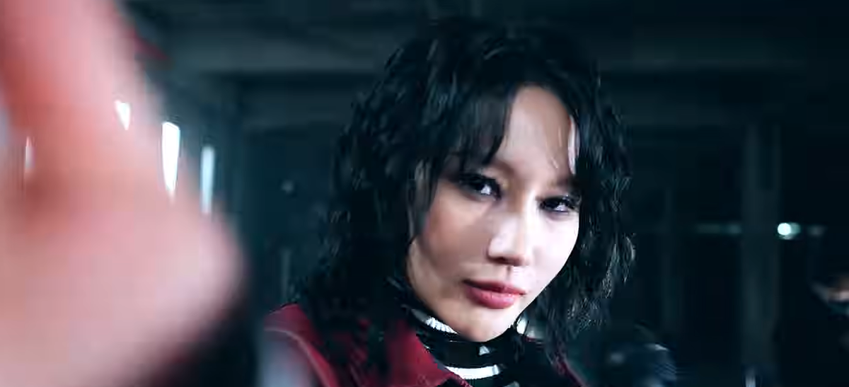 Siyeon, in red and black and with short black hair, looks into the camera.