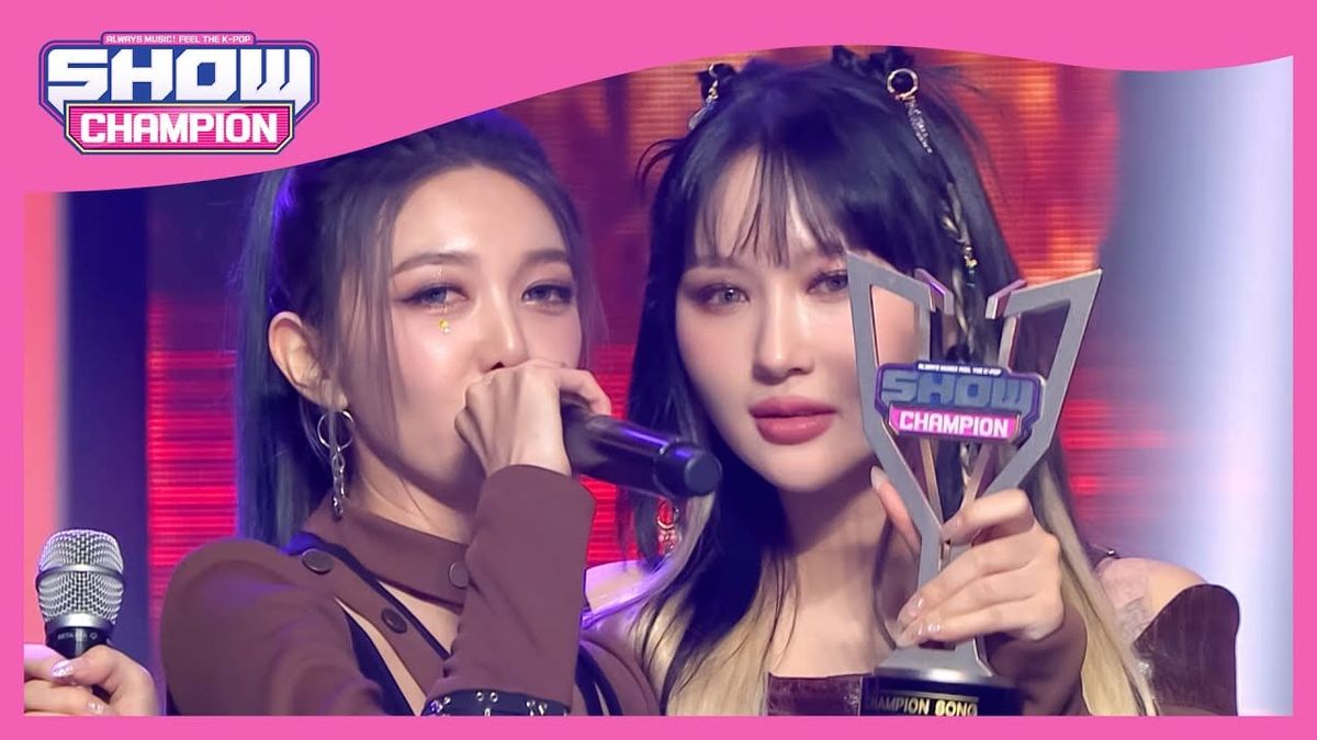 Dami holding the mic up and rapping as Siyeon shows off Dreamcatcher's 1st Music Show Trophy on Show Champion.
